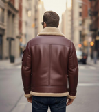 Man wearing a brown leather jacket with fur trim walking down a city street.

